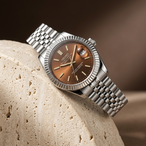 Brown dial watch on warm stone pedestal